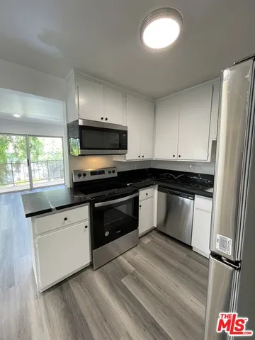 a kitchen with granite countertop a refrigerator and a stove top oven