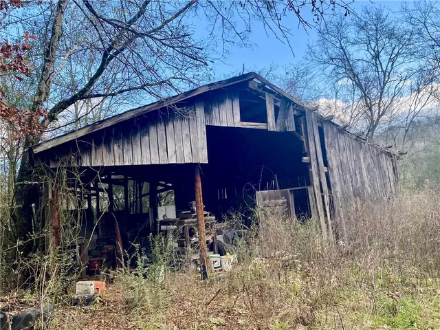a view of a wooden house with a small yard and large tree