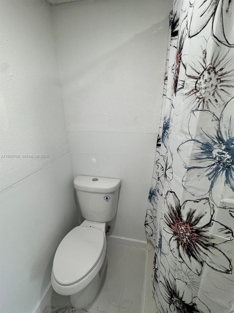 14281 Southwest 285th Street Homestead, FL 33033 - Photo 6 of 6 a white toilet sitting next to a shower curtain