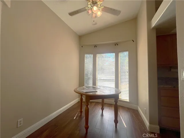 a view of a refrigerator in kitchen and an empty room with wooden floor
