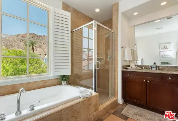a bathroom with a granite countertop tub sink and mirror