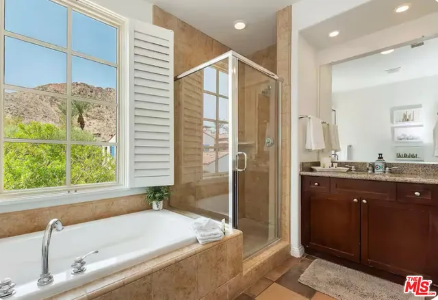 a bathroom with a granite countertop tub sink and mirror