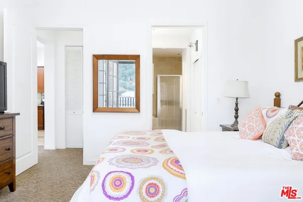 a bedroom with a bed and a lamp on dresser