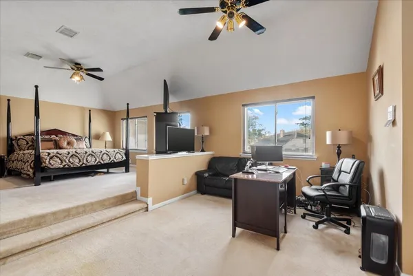 a bedroom with a bed a desk and chair with wooden floor