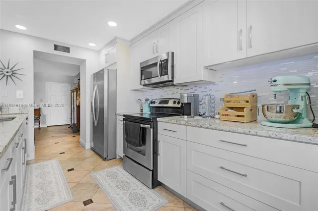 a kitchen with stainless steel appliances granite countertop a refrigerator a stove and a sink