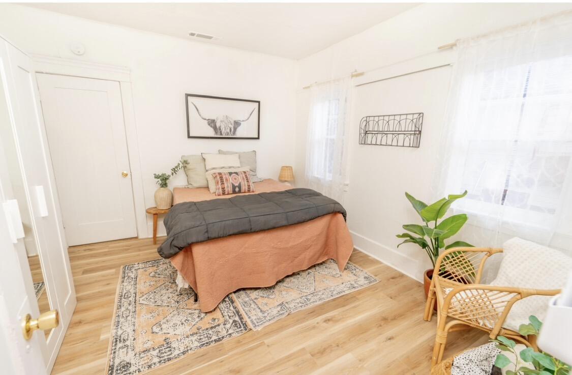 232 Ash Street Exeter, CA 93221 - Photo 12 of 13 a bedroom with a bed potted plant and wooden floor