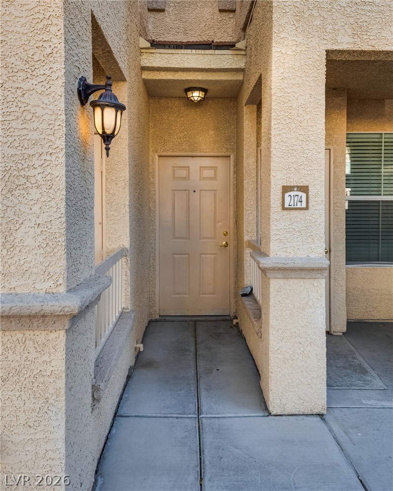 10550 West Alexander Road, Unit 2174 Las Vegas, NV 89129 - Photo 2 of 28 Welcoming entryway features classic stucco architecture and a covered concrete walkway.