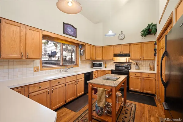 a kitchen with stainless steel appliances granite countertop a sink a stove a refrigerator cabinets and a dining table