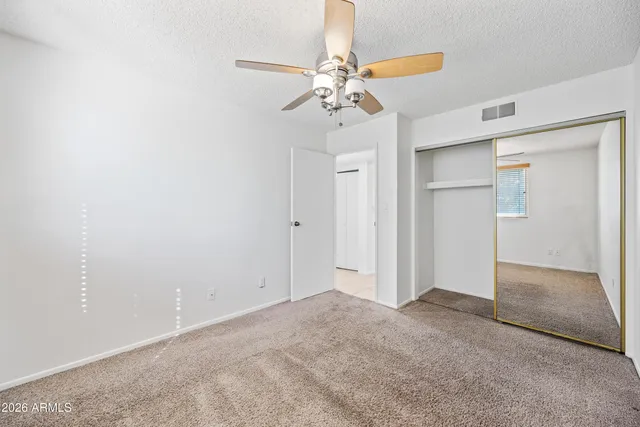 an empty room with a chandelier fan and closet