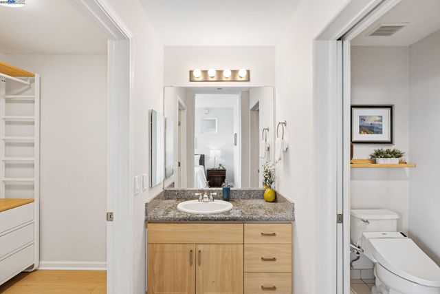 a bathroom with a granite countertop sink a toilet and a mirror