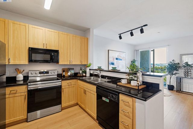 a kitchen with granite countertop a sink a stove top oven and cabinetry