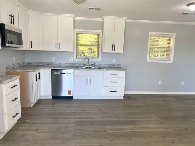 a kitchen with granite countertop a stove a sink and a microwave