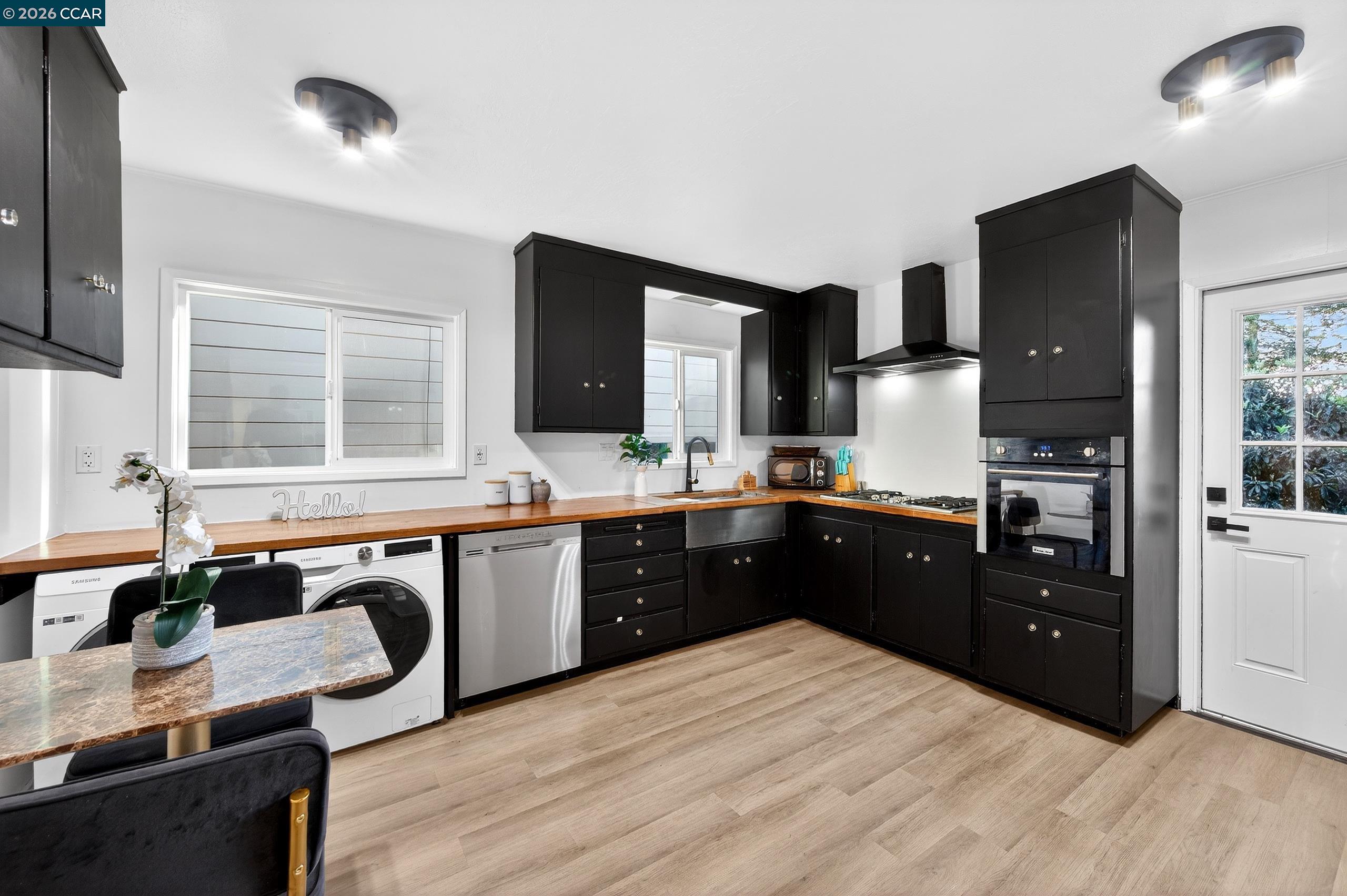 230 Fairlawn Drive Berkeley, CA 94708 - Photo 15 of 58 a kitchen with stainless steel appliances granite countertop a refrigerator a sink dishwasher a stove and a dining table with wooden floor