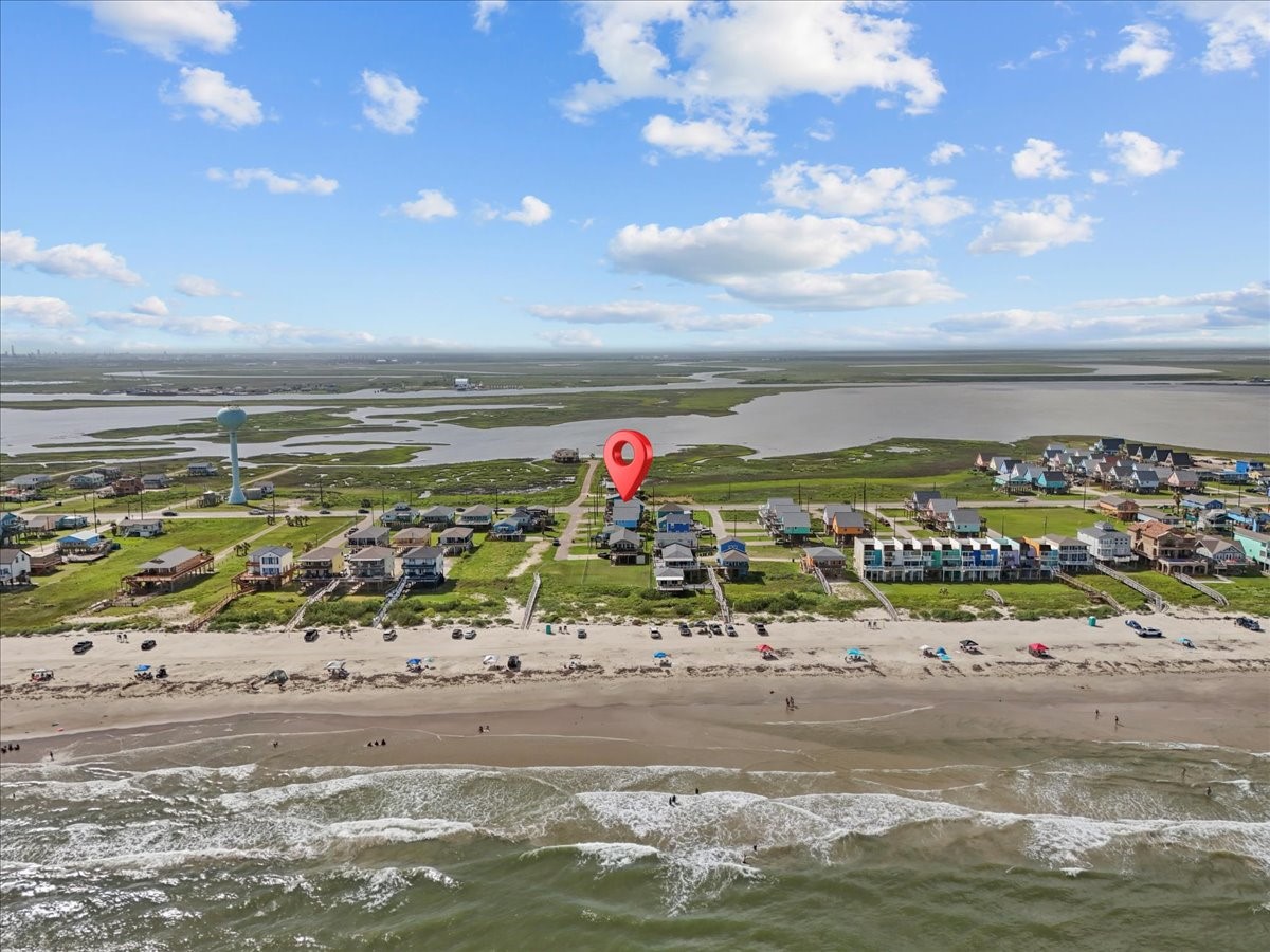 130 Beachcomber Avenue Surfside Beach, TX 77541 - Photo 31 of 33 This aerial photo showcases a beachfront community with charming homes lined along the coast. The property is marked, highlighting its proximity to the beach, offering scenic ocean views and easy access to sandy shores. Ideal for those seeking a coastal lifestyle.