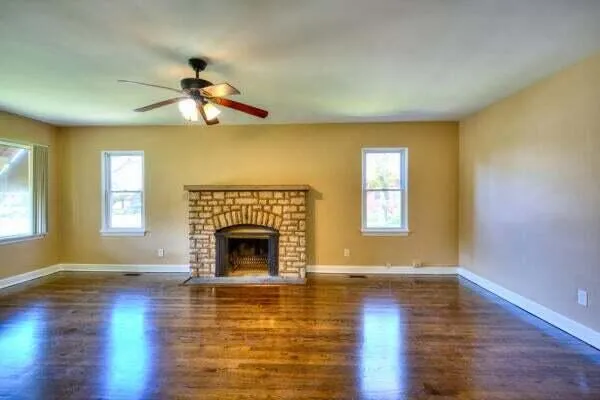 a living room with wooden floor a fireplace and a window