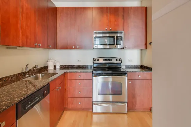 a kitchen with stainless steel appliances granite countertop a stove a sink and a microwave