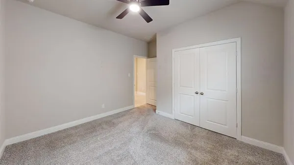 a view of an empty room and chandelier fan