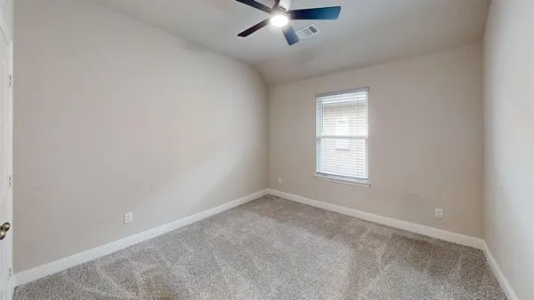 an empty room with ceiling fan and windows