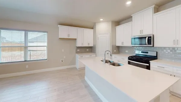 a kitchen with stainless steel appliances a stove a sink a microwave a refrigerator and cabinets