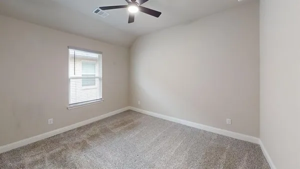 an empty room with chandelier fan and windows