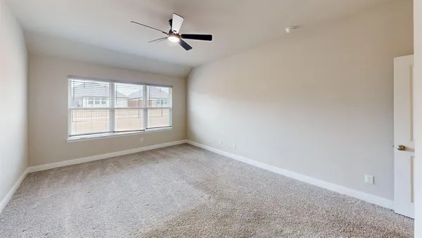 an empty room with windows and ceiling fan