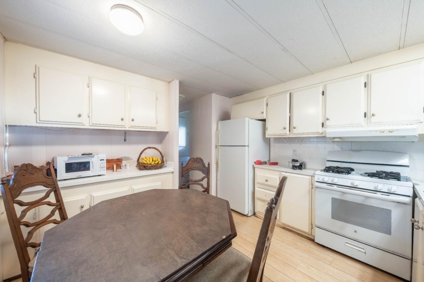 13624 Monte Del Sol, Unit 142 Castroville, CA 95012 - Photo 8 of 25 a kitchen with stainless steel appliances granite countertop a stove a refrigerator a white table and chairs with wooden floors