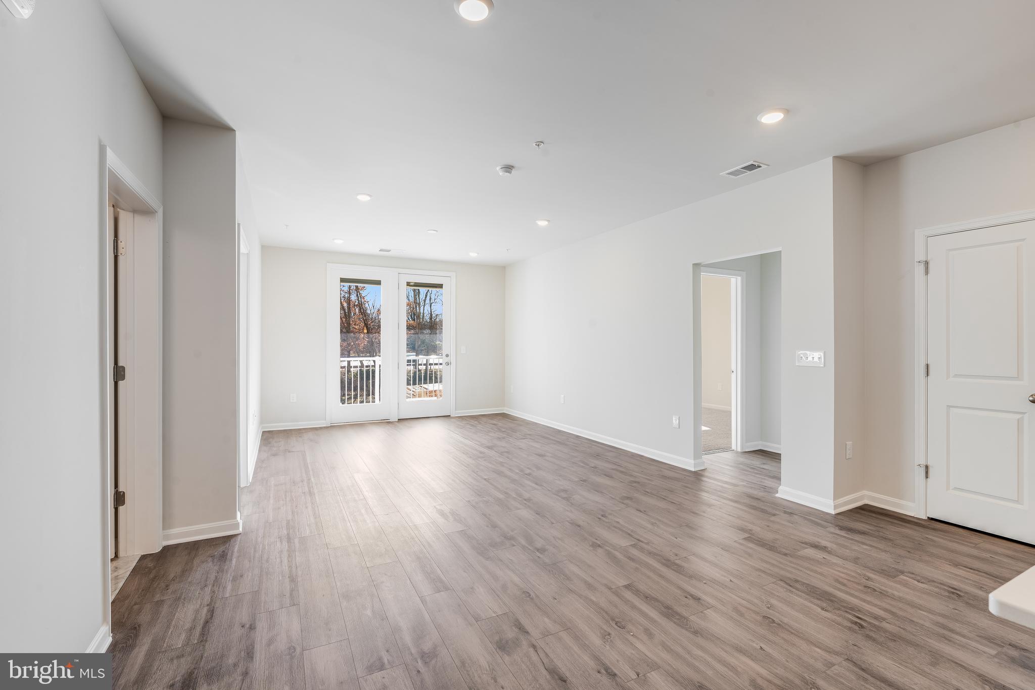 4003 Seaside Alder Road, Unit 409 LILAC Bowie, MD 20720 - Photo 8 of 24 a view of an empty room with wooden floor and a window