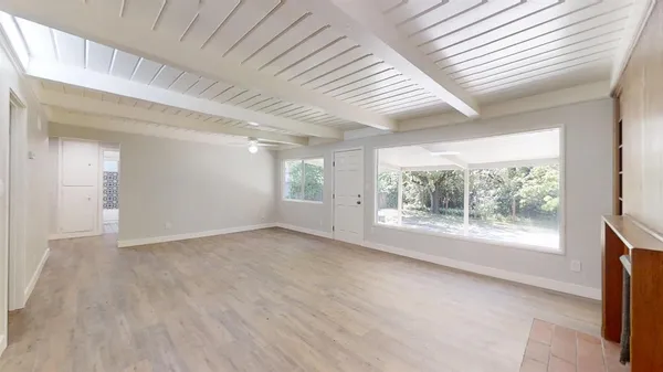 an empty room with windows fireplace and wooden floor