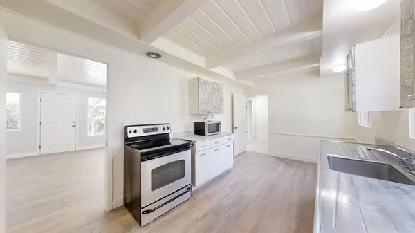 an empty room with wooden floor chandelier fan and windows