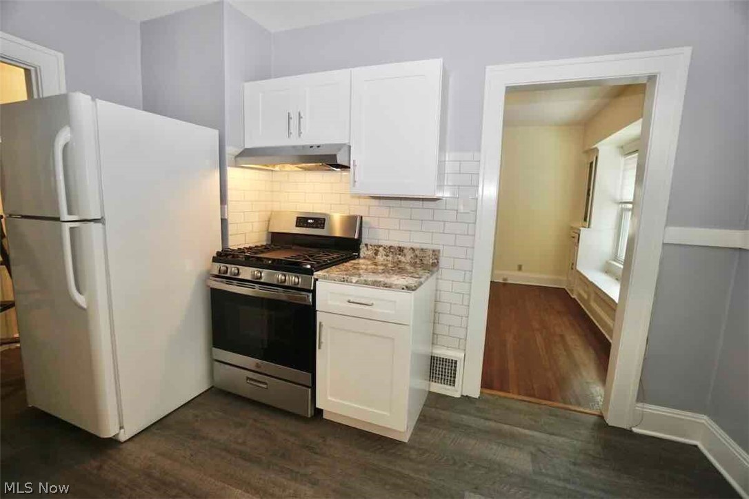 2168 Edgewood Road Cleveland, OH 44118 - Photo 9 of 41 1st fl. kitchen featuring white refrigerator, "Lifeproof" flooring, white cabinets, and stainless steel range with gas stovetop and subway tile backsplash.