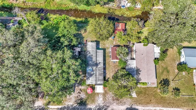 an aerial view of residential house with outdoor space and trees all around