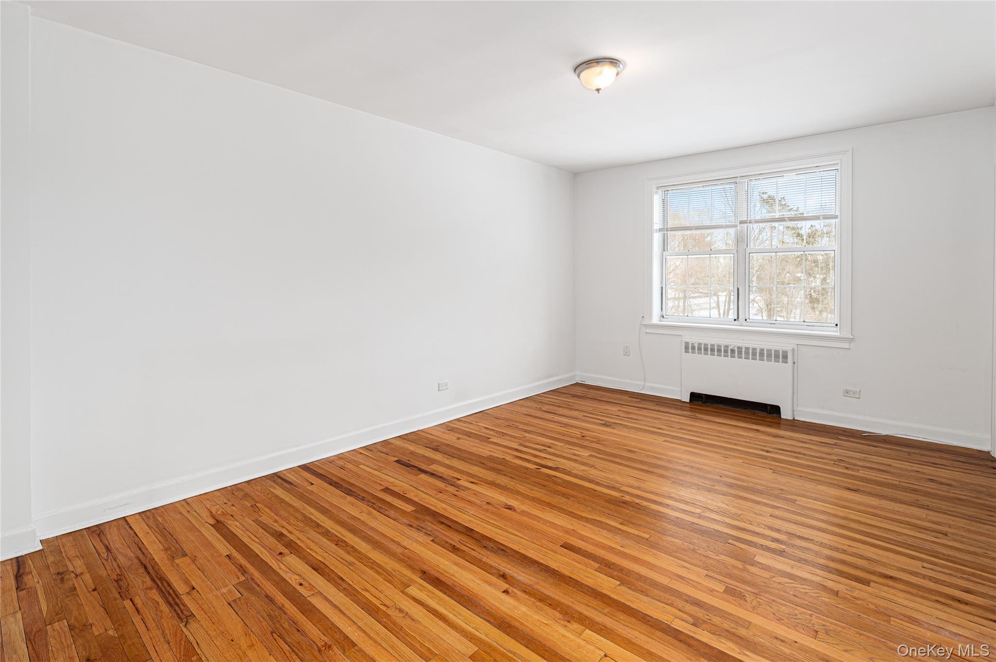 633 Old Post Road, Unit 34 Bedford, NY 10506 - Photo 2 of 14 an empty room with wooden floor and windows
