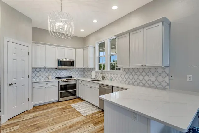 a kitchen with stainless steel appliances granite countertop a stove top oven a sink dishwasher and a refrigerator with wooden floor