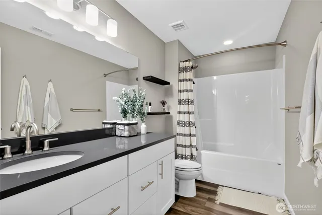 a bathroom with a granite countertop sink a toilet and shower