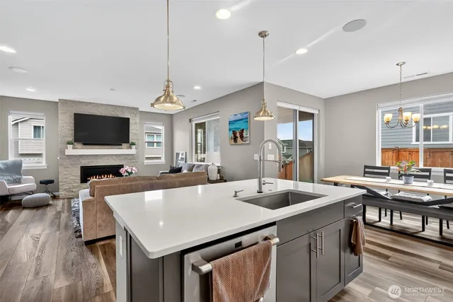 a kitchen with a stove a counter top space a sink dishwasher and living room view