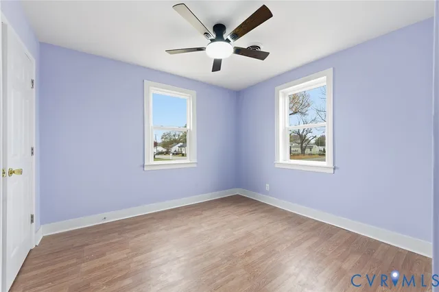an empty room with ceiling fan and windows