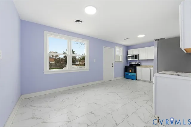a view of a kitchen with furniture and stainless steel appliances