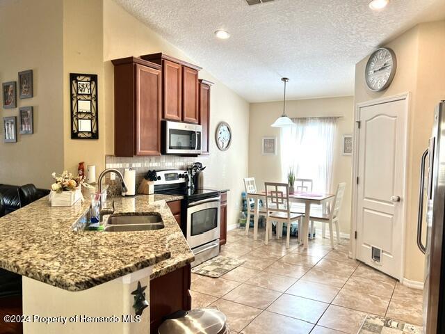18430 Waydale Loop Hudson, FL 34667 - Photo 8 of 30 a kitchen with stainless steel appliances granite countertop a stove top oven a sink a dining table and chairs