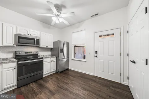 a kitchen with stainless steel appliances a stove top oven a refrigerator cabinets and wooden floor