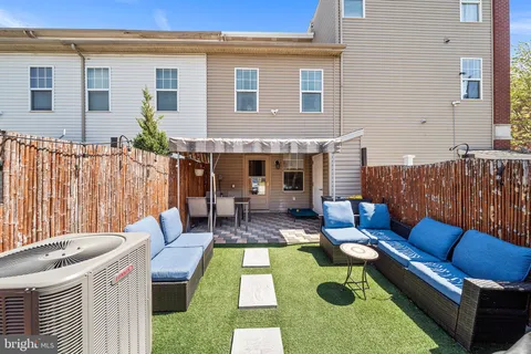 a view of a patio with couches table and chairs with wooden fence