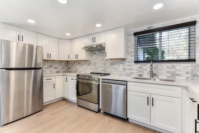 an empty room with wooden floor a fireplace and windows