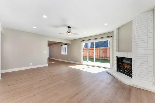 an empty room with wooden floor fan and windows