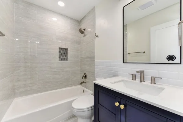 a view of an empty room with wooden floor and a ceiling fan