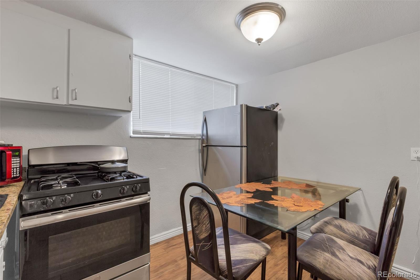 326 South Alcott Street Denver, CO 80219 - Photo 9 of 21 a kitchen with stainless steel appliances granite countertop a stove a refrigerator and a view of dining table