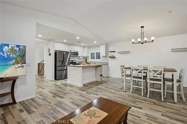 a kitchen with stainless steel appliances kitchen island granite countertop a table chairs and a refrigerator