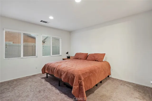 a bed sitting in a spacious bedroom next to a window