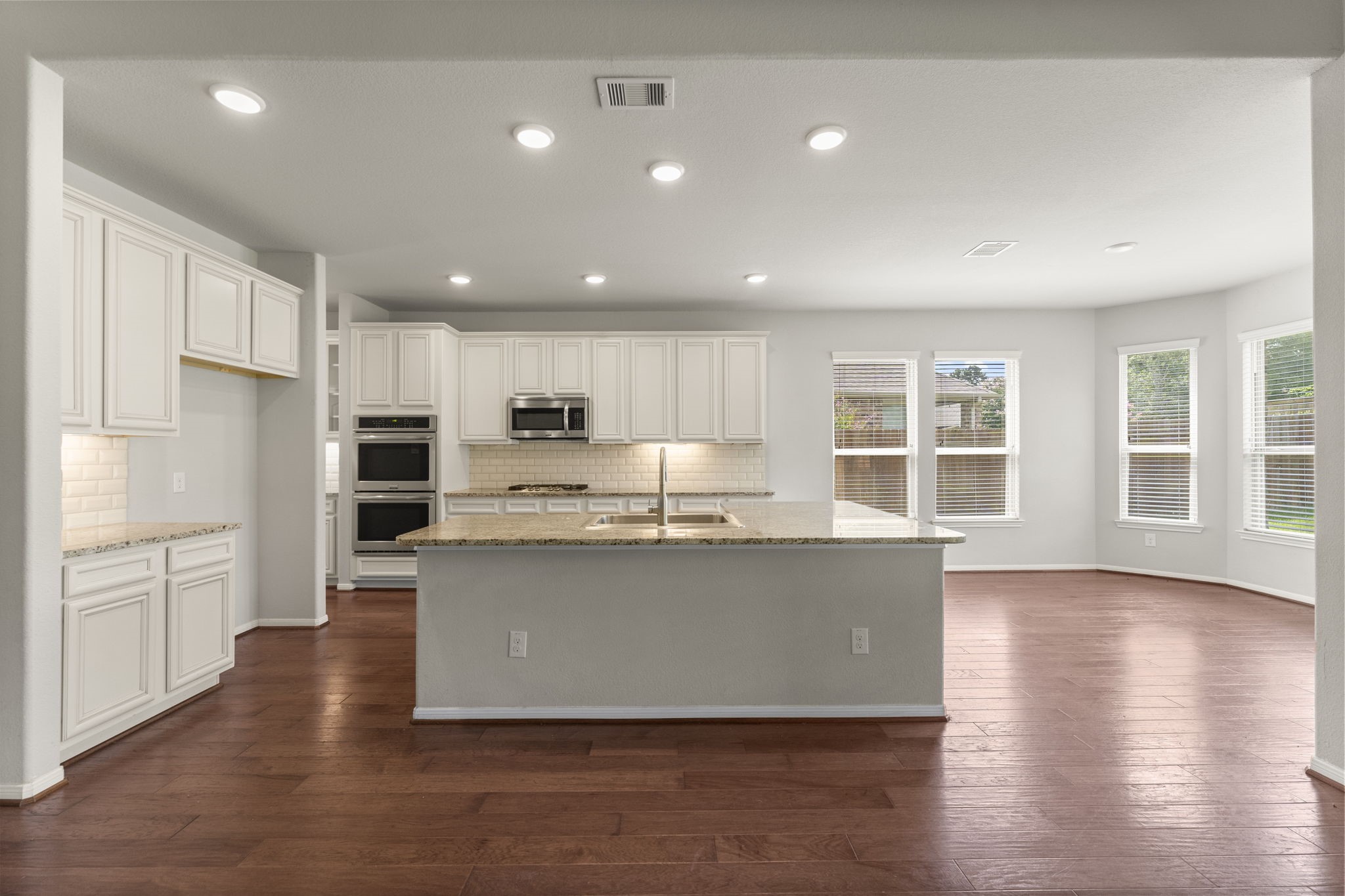 5015 Gold Lantana Trail Spring, TX 77389 - Photo 17 of 50 a kitchen with stainless steel appliances granite countertop a sink a stove a refrigerator and island with wooden floors