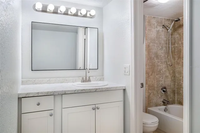 a bathroom with a granite countertop sink vanity mirror shower and a bathtub