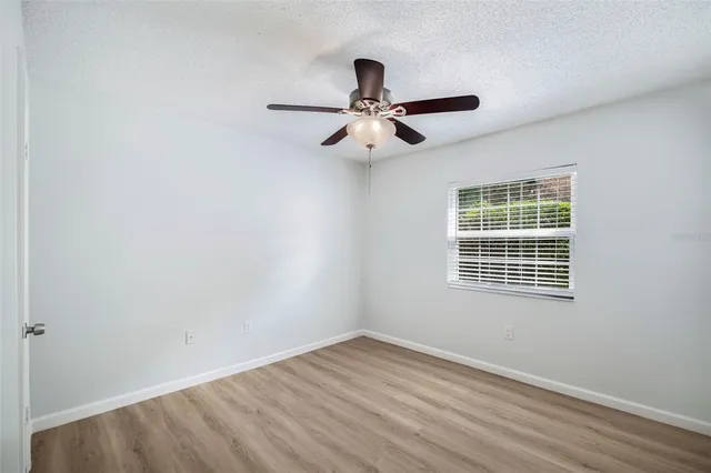 a view of empty room with wooden floor and fan