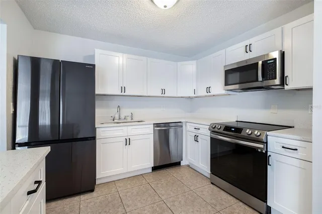 a kitchen with stainless steel appliances granite countertop white cabinets and black stove top oven